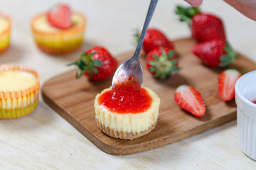 Mini strawberry cheesecake on a bamboo cutting board.