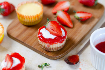 Mini strawberry cheesecake on a bamboo cutting board.