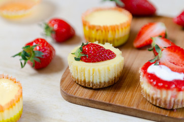 Mini strawberry cheesecake on a bamboo cutting board.