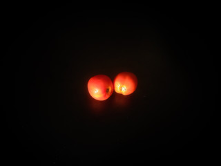 red tomatoes of different sizes isolated on black background