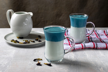 Latte Matcha Dalgona Blue Pea. Hot fresh milk with blue butterfly pea flowers or clitoria ternatea latte in a glass cup. Horizontal orientation