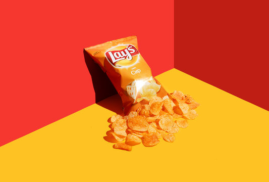 Kiev, Ukraine - May 8, 2020: open packet of Lays chips on a red-yellow background. Flying chips