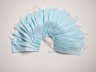 Multiple Light Blue Face Masks fanned out against a white background. Photographed with a shallow depth of field.