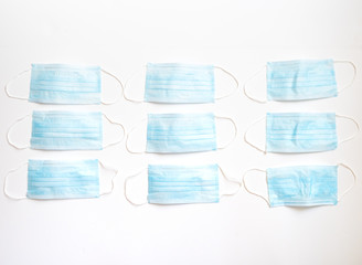 Nine Light Blue Disposable Face Masks photographed against a white background with a shallow depth of field.