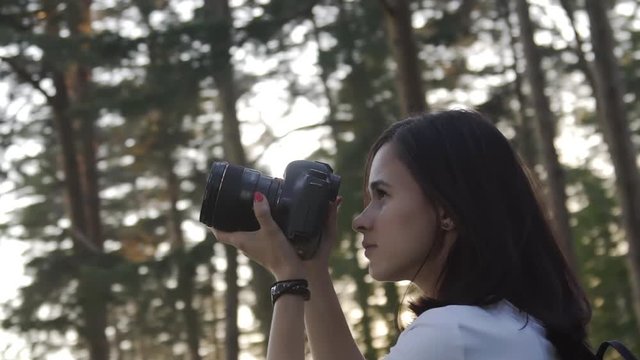 Traveler photographing scenic view in forest. One caucasian woman shooting close up look. Girl take photo video on dslr mirrorless camera. Professional photographer travel with backpack. Outdoor.