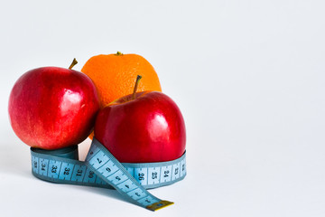 diet food for weight loss. red apples and orange wrapped with measuring tape. Place for text