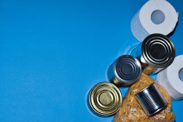 Food delivery on quarantine isolation on a blue background side view. Macaroni, buckwheat, canned food, talet paper.