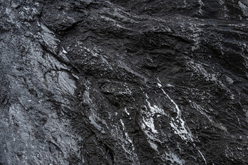 Aged shabby cliff face with cracks. Rough black stone, dark rock texture of mountains, background  for text on theme geology.