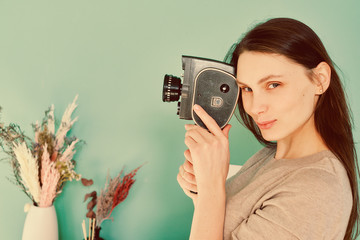 beautiful girl in blue jeans with a retro camera th in hands on a turquoise background, look at the...