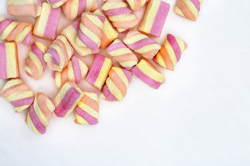 Sweet striped pink and yellow marshmallows on white background with copy space. Confectionery.