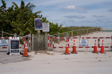 Fototapeta na wymiar MIAMI, USA - MAY 3, 2020: Beach closed due to COVID-19. Warning sign in a desolate tropical beach. Miami covid time, Florida. Beach closed coronavirus sign, shutdown concept, covid 19 fears and panic.