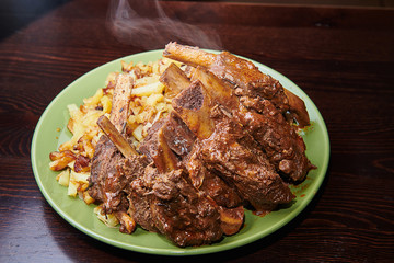 Dish of deer ribs with boiled potatoes on a dark background