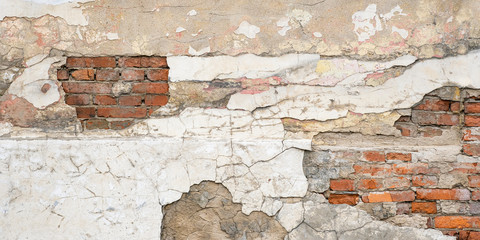 Old weathered red brick wall with pieces of whitewash or concrete, mortar, putty, plaster. Wide fragment of abandoned wall, surface building with chips, cracks and damages.