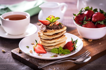 Pancakes  with chocolate sauce and fresh  strawberries on brawn wooden background. Delicious sweet dessert.