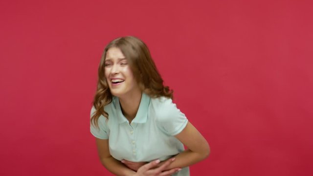 Hilarious laughter. Carefree positive young brunette woman in polo t-shirt laughing out loud after hearing funny anecdote, chuckling and feeling amused by joke. studio shot isolated on red background