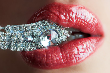 Close-up of beautiful womans lips with bright fashion dark red glossy makeup. Macro lipgloss cherry...