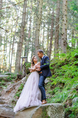 Naklejka na ściany i meble An attractive newlywed couple, a happy and joyful moment. A man and a woman shave and kiss in holiday clothes. Bohemian-style wedding cermonia in the forest in the fresh air.