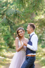 Obraz premium An attractive newlywed couple, a happy and joyful moment. A man and a woman shave and kiss in holiday clothes. Bohemian-style wedding cermonia in the forest in the fresh air.