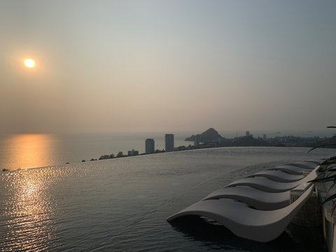 March-12-2019 : Hua Hin, Thailand : Poolside lounge chairs next to an infinity pool sunset, luxurious infinity swimming pool at sunset in Holiday Inn Resort Vana Nava Hua Hin