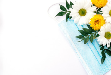 Protective mask decorated with flowers  on a white background.Concept of the end of quarantine due to the coronavirus pandemic.Copy space for text