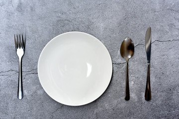 Top view of empty plate spoon fork and knife on Dark color background. concept of a restaurant bistro dining cafe serving. Selected focus.