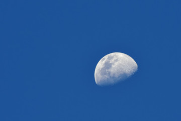 Moon over blue sky background / The Moon as it appears early in its first quarter or late in its last quarter, when only a small arc-shaped section of the visible portion is illuminated by the Sun.