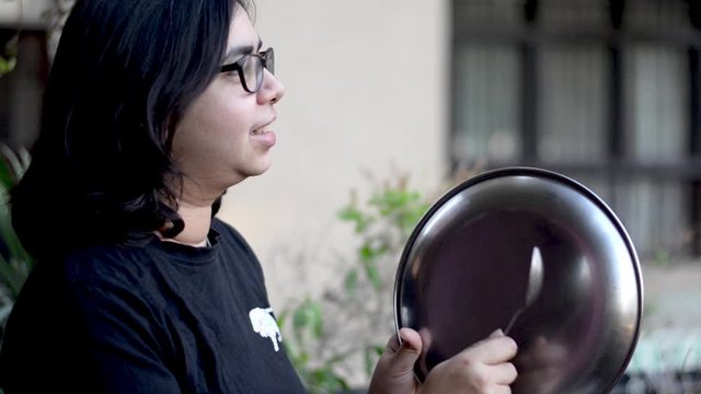 Young Indian girl making noise with a plate and spoon as a mark of respect for essentia l healthcare workers, medical personel, doctors, policemen and more during the coronavirus lockdown in India