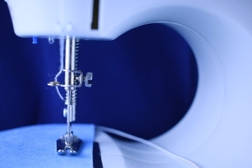 Close up de maquina de coser, con aguja. 
La maquina cose cubrebocas