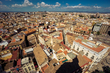 Obraz premium Scenic view from the height of the cathedral in the center of Valencia. Many tile roofs on a background of bright clouds. Typical landscape of Spain