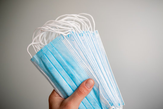 Close-up of hand offering protective face mask. Surgical mask on hand. COVID-19, Coronovirus concept. Medical mask on a white background.