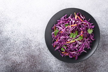 Red cabbage coleslaw with carrot on a light background, top view, place for text. Healthy food concept. 