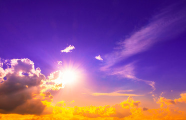 Orange sun light in clouds in purple sky and bright sun
