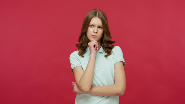 Need to think! Pensive doubting woman in polo t-shirt pondering and imagining in mind, wondering difficult solution, feeling confused, not sure about choice. studio shot isolated on red background