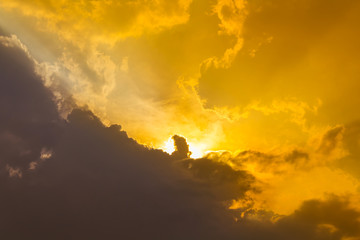 Orange sunset light on sky and shadows black clouds