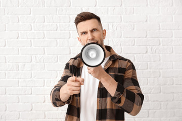 Emotional young man with megaphone on white background