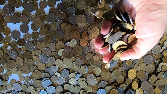 Girl picks up handful of coins in her hand and throws it over coins on table