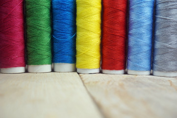 Colorful spools of thread on wooden table                              