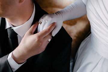 Groom holds bride's hand in a white glove