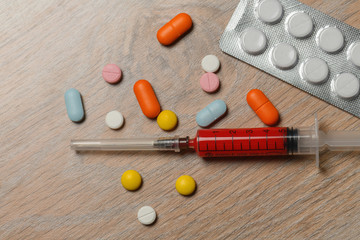 Concept of treatment options for COVID virus infection. Colorful syringes and tablets close-up.