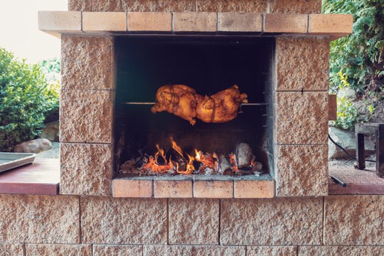 chicken roasting on a spit in garden grill with open fire
