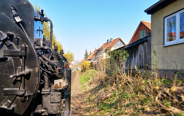 Steam locomotive drives past the houses in Wernigerode. Dynamic due to motion blur.