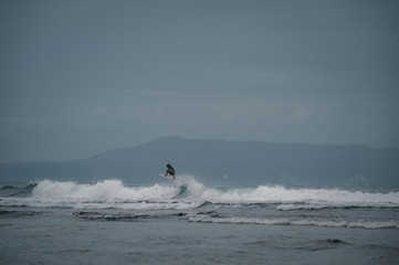 Young people ride on short boards, perform bright tricks on the waves during sunset.