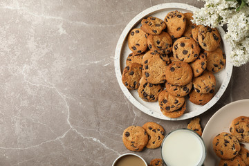 Composition with tray of chocolate chip cookies on light brown table. Sweet breakfast