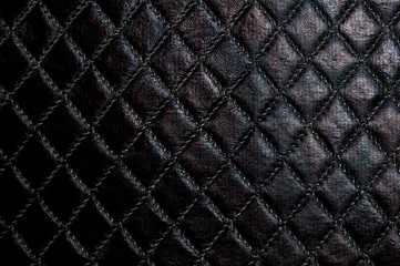 Artificial leather of dark brown color. Faux leather texture with a diamond pattern.