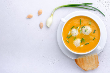 Pumpkin cream soup with rice dumplings on a white concrete background with copy space. Healthy eating.