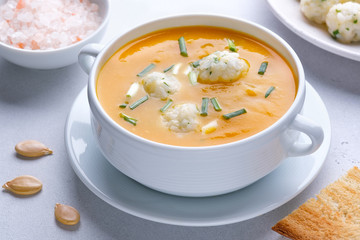 Pumpkin cream soup with rice dumplings on a white concrete background with copy space. Healthy eating.