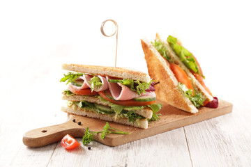 club sandwich with ham, tomato, lettuce and cucumber on wooden board