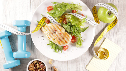 grilled chicken fillet with salad- dumbbell and meter tape- diet food concept