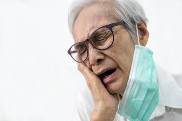 Sad senior woman holding her hand on her aching tooth,asian elderly suffering from toothache and...