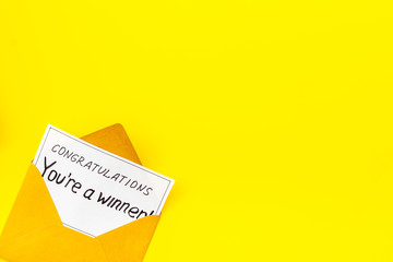 You're a winner. Envelope with congratulation card on yellow table top view copy space